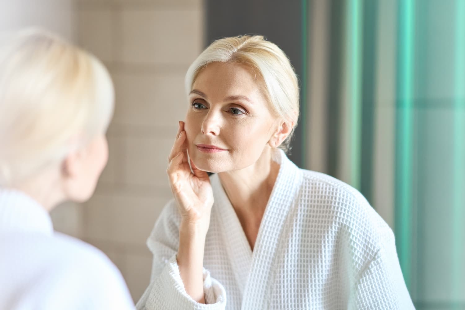 Older woman examining her face in the mirror